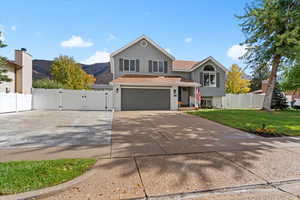 View of front facade with a gate, concrete driveway, a garage, a mountain view, and roof with shingles