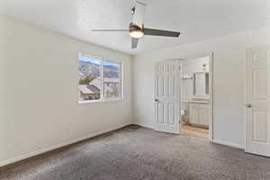 Unfurnished bedroom with light carpet, a textured ceiling, a ceiling fan, and ensuite bath