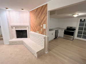 Kitchen featuring white cabinetry, stainless steel appliances, a brick fireplace, light carpet, and wooden walls