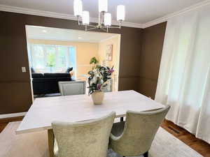 Dining area featuring ornamental molding, wood finished floors, and a chandelier