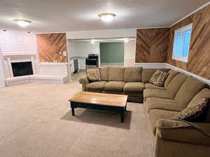 Living room featuring wood walls, light carpet, a textured ceiling, and a fireplace