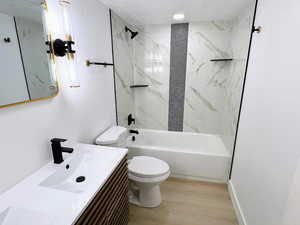 Bathroom with bathing tub / shower combination, light wood finished floors, vanity, and a textured ceiling