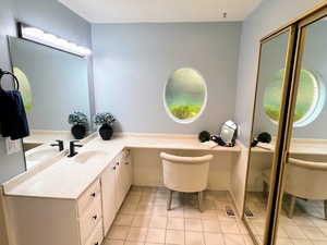 Bathroom with light tile patterned floors, vanity, a garden tub, and healthy amount of natural light