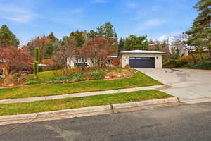 View of front of home featuring driveway, brick siding, a front lawn, and a garage