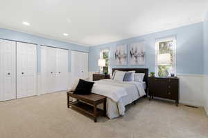 Carpeted bedroom featuring multiple closets and ornamental molding
