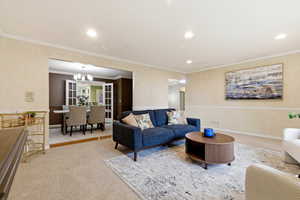 Carpeted living area featuring french doors, ornamental molding, recessed lighting, and a chandelier