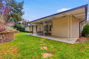 Back of house featuring a ceiling fan, brick siding, a patio area, and a yard