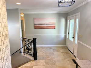 Entryway with a chandelier, crown molding, recessed lighting, and light stone finish floors