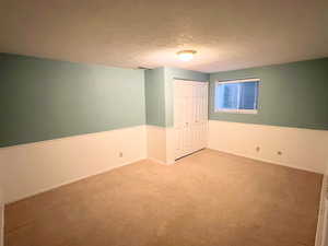 Unfurnished bedroom with a textured ceiling, a closet, and carpet floors