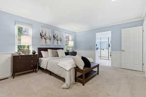 Bedroom with light colored carpet, ornamental molding, and ensuite bathroom