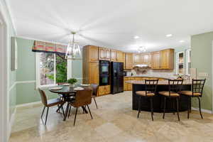 Kitchen with a kitchen breakfast bar, a peninsula, black appliances, a chandelier, and decorative light fixtures