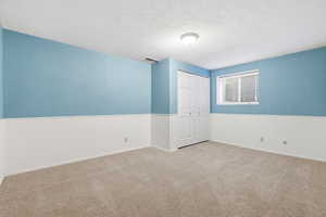 Carpeted spare room with a textured ceiling and wainscoting