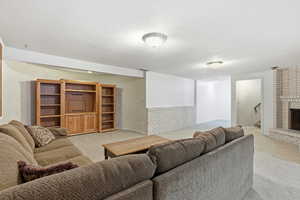 Living area with light carpet, a textured ceiling, and a fireplace