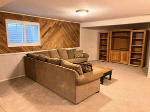 Living area featuring wooden walls, light colored carpet, and a textured ceiling