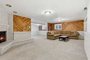 Living room with wood walls, a fireplace, carpet floors, and wainscoting