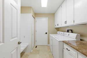 Laundry room featuring separate washer and dryer and cabinet space