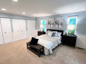 Carpeted bedroom with multiple closets, ornamental molding, and recessed lighting