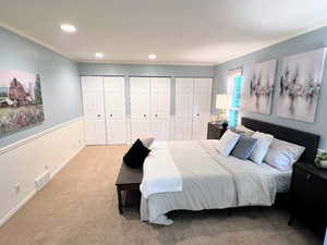Carpeted bedroom featuring two closets, crown molding, and recessed lighting