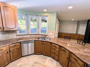 Kitchen with light stone countertops, dishwasher, recessed lighting, and brown cabinetry
