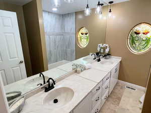 Full bath with double vanity and baseboards