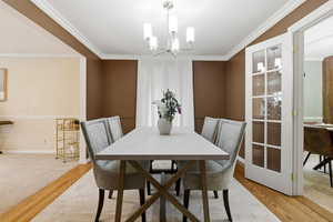 Dining room featuring a chandelier, crown molding, and light wood-style floors