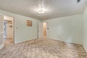 Unfurnished bedroom with a textured ceiling and carpet