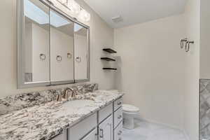 Half bath with vanity and light marble finish floors