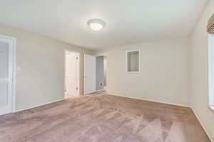 Unfurnished bedroom with light colored carpet and baseboards