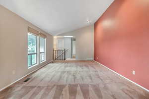 Spare room with light carpet and vaulted ceiling