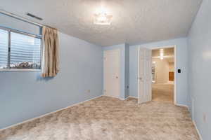 Unfurnished bedroom featuring carpet and a textured ceiling