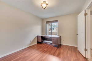 Unfurnished office with light wood-style flooring and baseboards