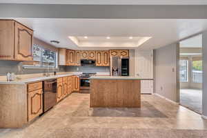 Kitchen featuring a raised ceiling, stainless steel appliances, light countertops, light tile patterned floors, and recessed lighting