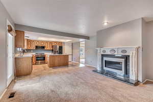 Kitchen featuring open floor plan, light countertops, light carpet, and a kitchen island