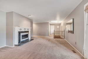 Unfurnished living room with light carpet, a fireplace, and a skylight