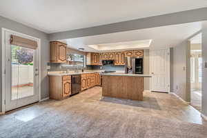 Kitchen with light tile patterned floors, light countertops, stainless steel appliances, a center island, and light carpet