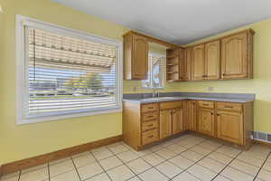 Kitchen featuring light tile patterned floors, open shelves, light countertops, and brown cabinetry