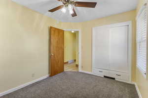 Unfurnished bedroom with carpet flooring, a closet, a textured ceiling, and a ceiling fan