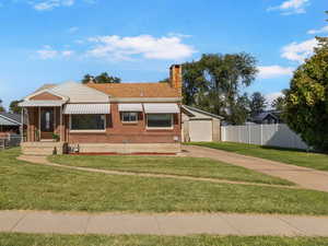View of front of house featuring a chimney, brick siding, a garage, and driveway