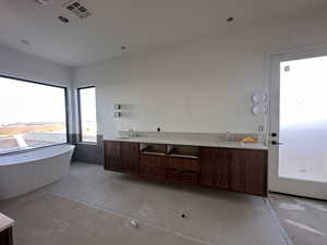 Bathroom featuring double vanity, a freestanding bath, and light tile patterned floors