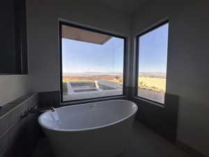 Full bath with a freestanding tub, healthy amount of natural light, tile walls, and dark tile patterned floors
