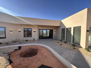 View of exterior entry featuring stucco siding and a patio
