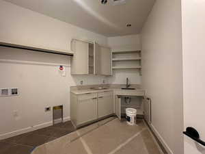 Laundry area with electric dryer hookup, dark tile patterned flooring, washer hookup, and cabinet space
