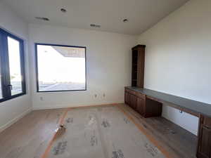 Unfurnished office with built in desk and wood finished floors