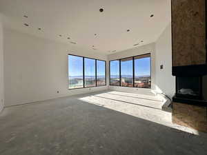 Unfurnished living room with a large fireplace, a mountain view, and unfinished concrete flooring