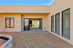 View of exterior entry with a patio and stucco siding