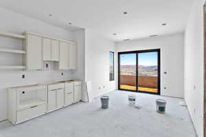 Kitchen featuring concrete flooring, open shelves, and white cabinets
