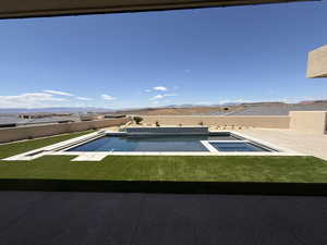 Integrated pool / hot tub featuring a mountain view and a fenced backyard