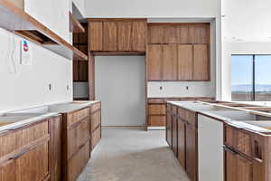 Kitchen featuring unfinished concrete flooring, wood finish cabinets, and open shelves