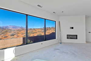 Unfurnished living room featuring concrete floors, a glass covered fireplace, and a mountain view