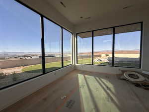 Unfurnished sunroom featuring wood-type flooring, healthy amount of natural light, and a mountain view